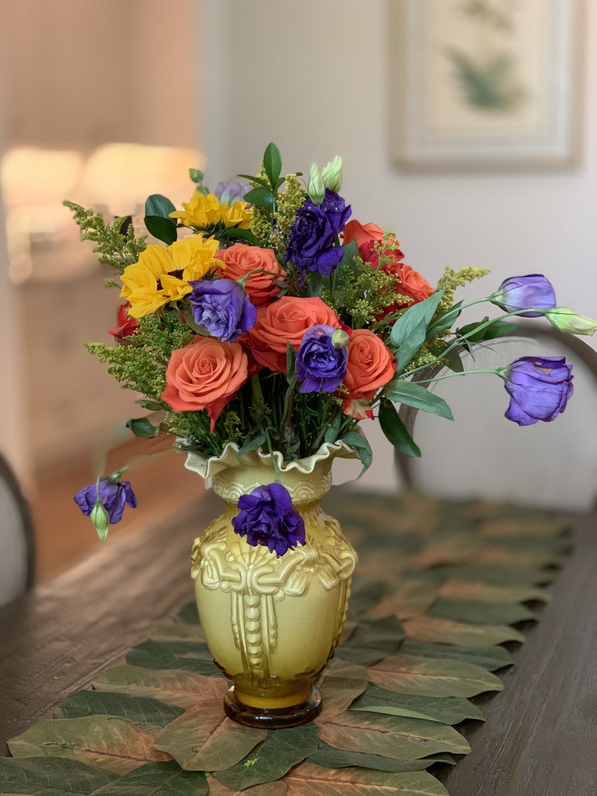 Coral roses, yellow flowers and purple lisianthus in a green ceramic vase