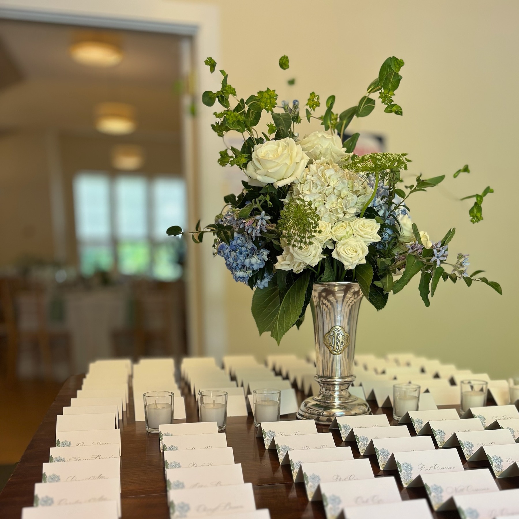 Tall floral arrangement above rows of wedding escort cards