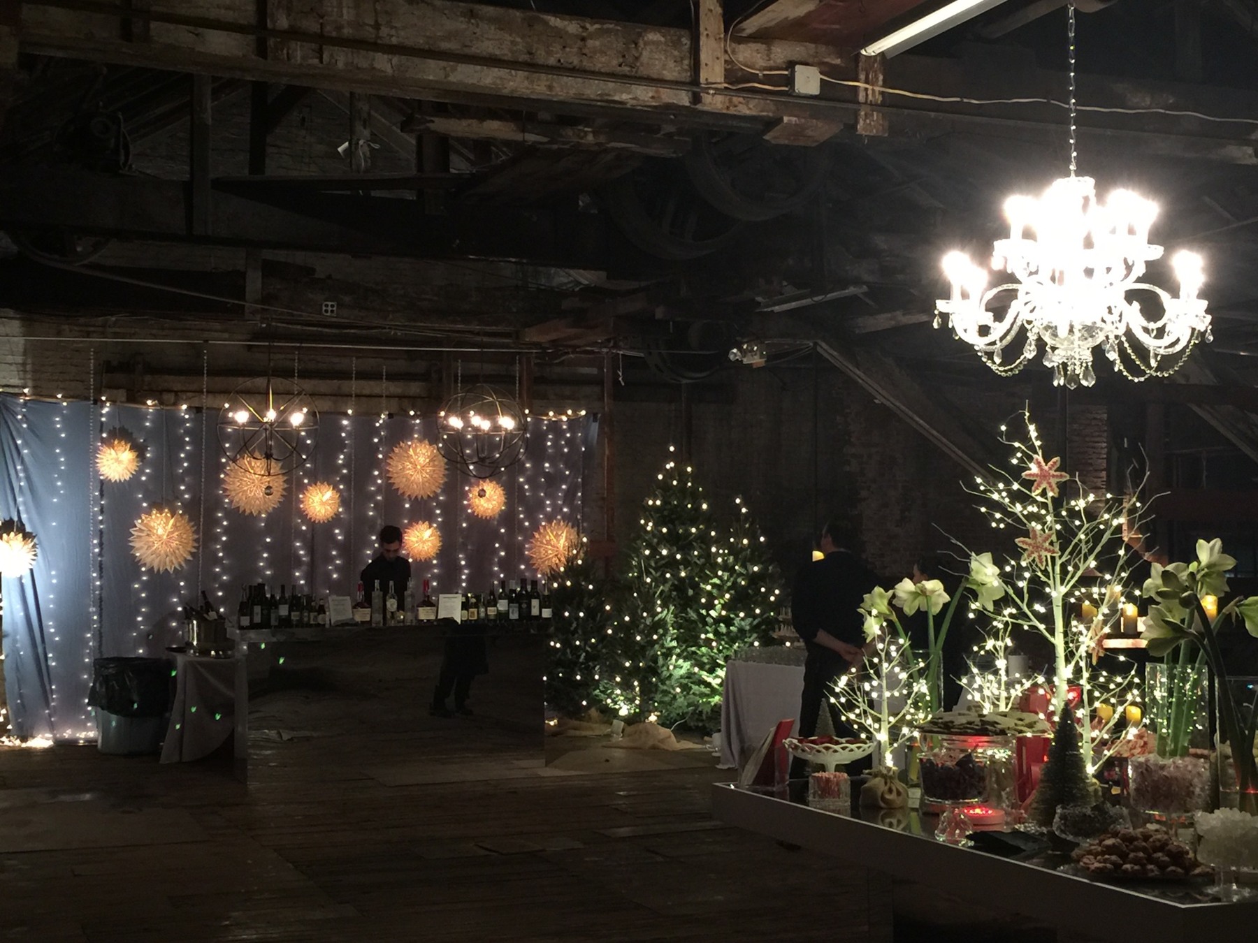Holiday gathering space with a chandelier, illuminated branches and decorated tables