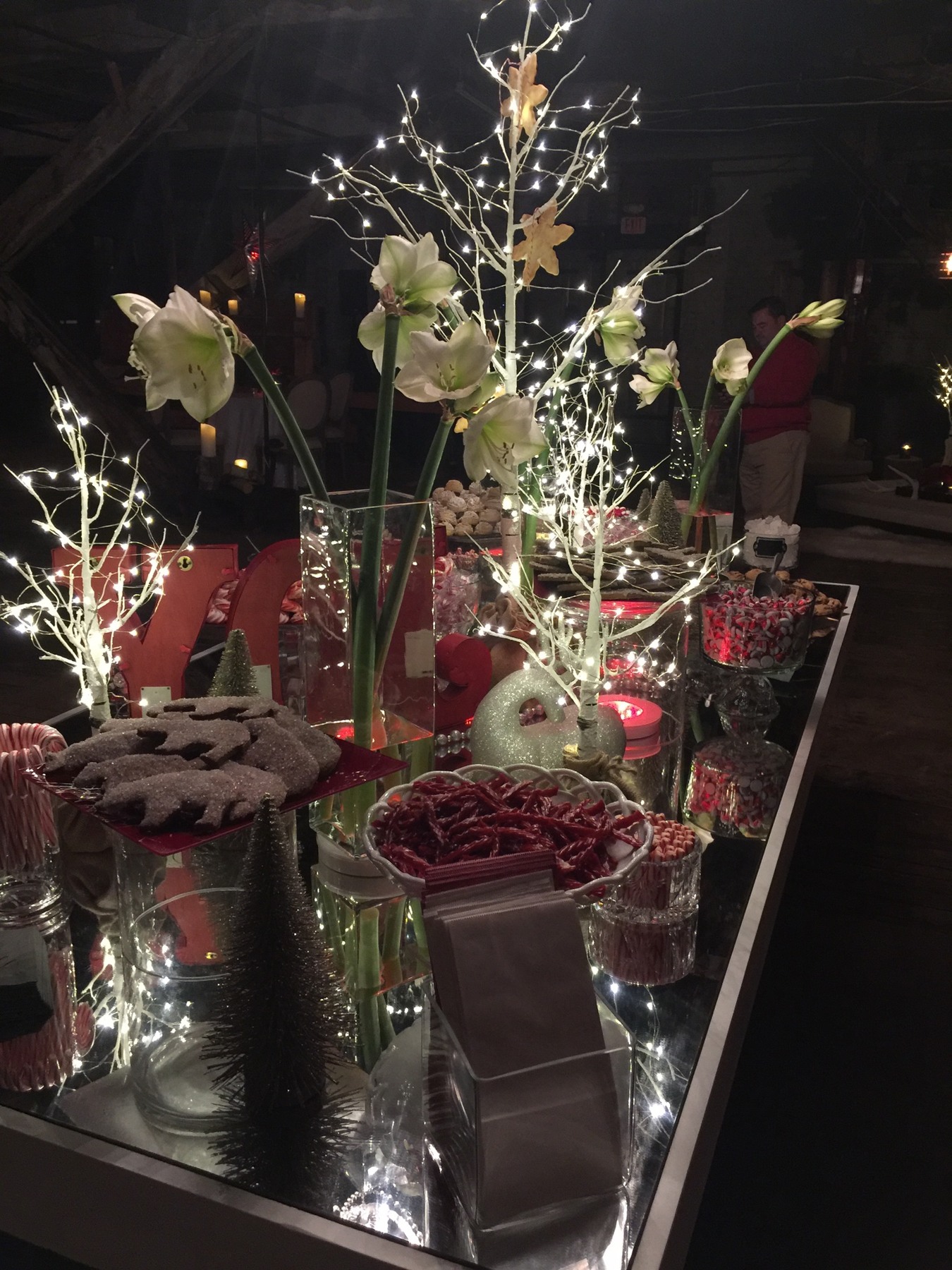 Mirrored holiday display with flowers, red decorations and illuminated branches