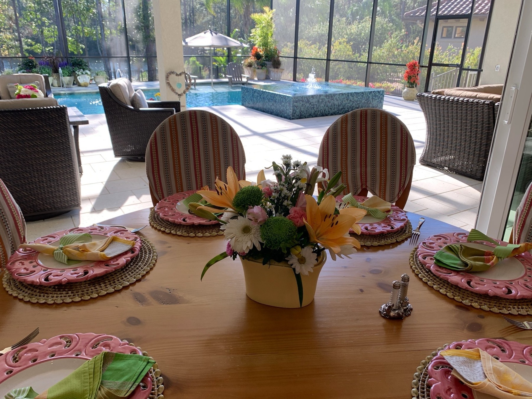 Pink plates, green napkins and colorful flowers on an indoor dining table