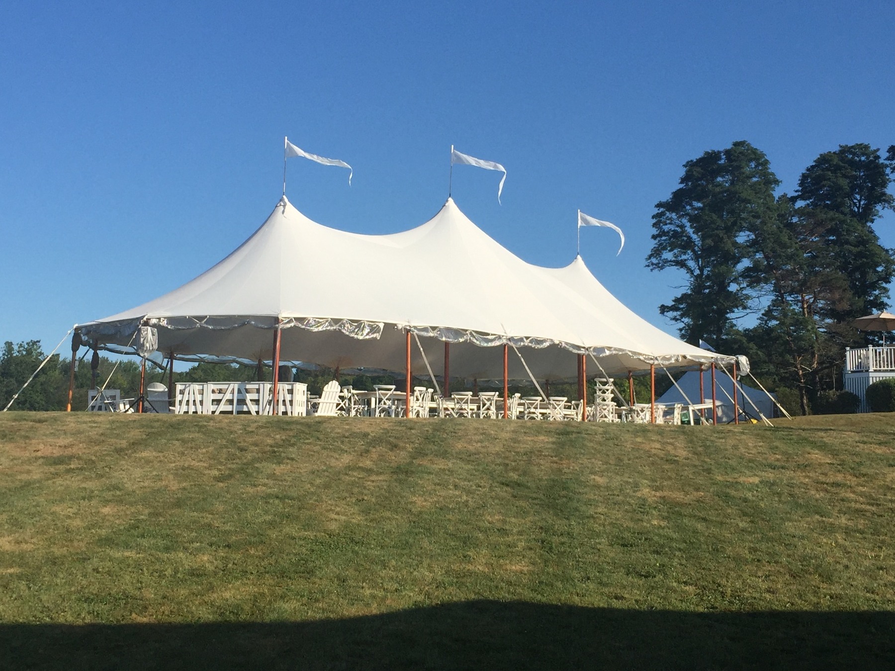 Large white sailcloth tent on a lawn under a blue sky