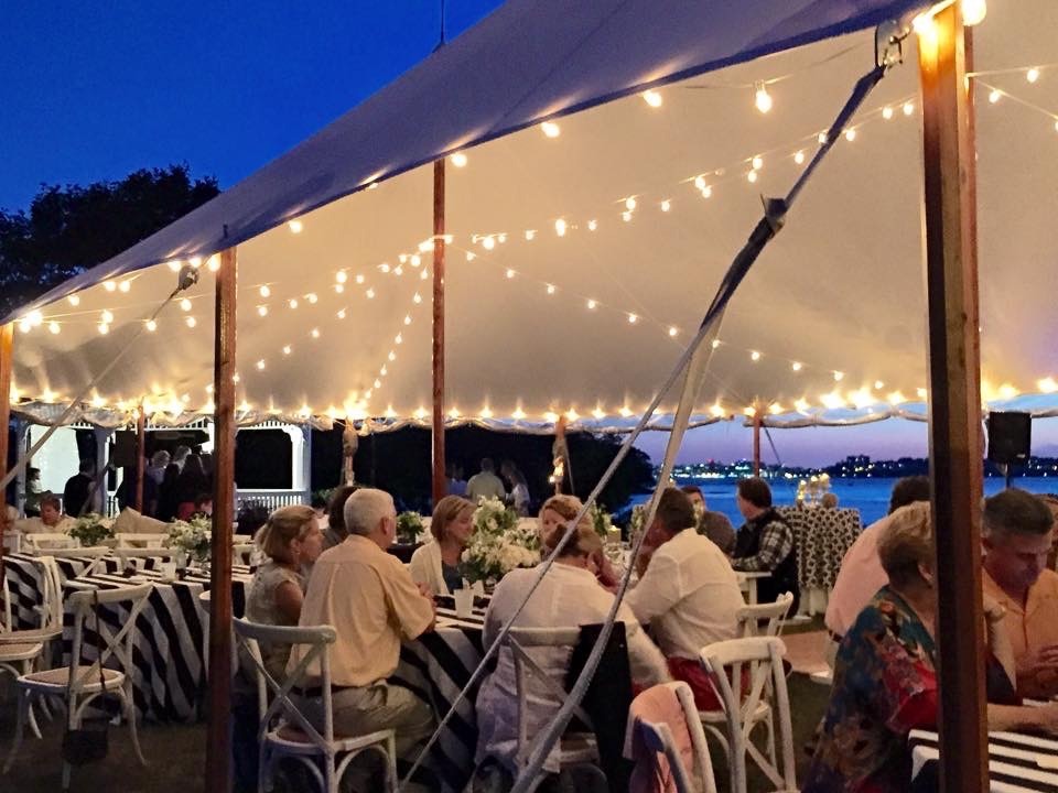 Wedding guests at a tented garden reception under string lights