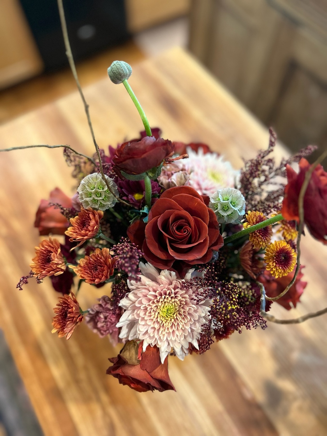 Red roses, orange flowers and pale pink chrysanthemums viewed from above