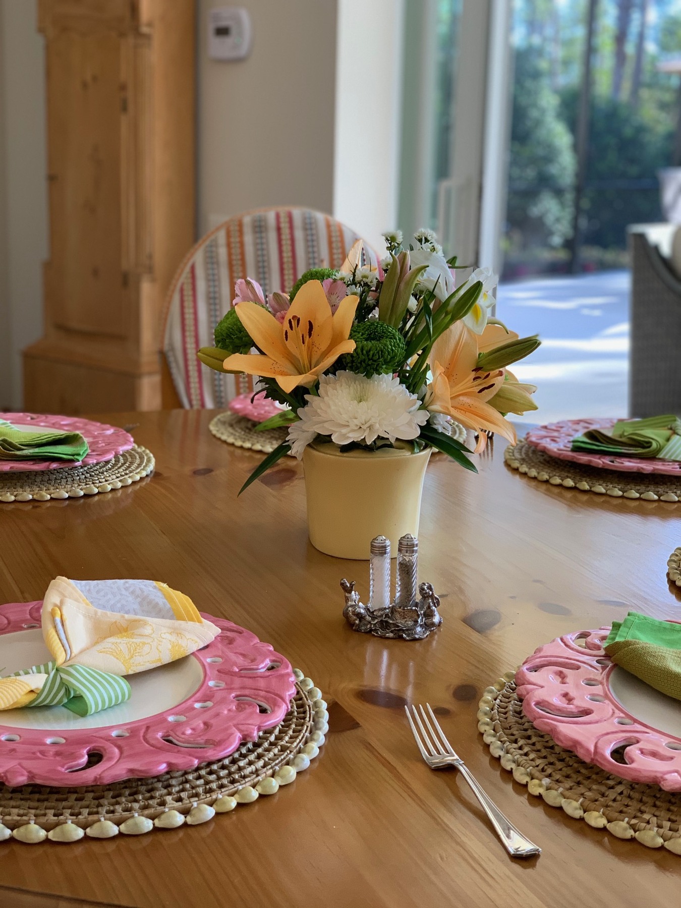 Yellow lilies and white flowers beside pink plates and colorful napkins