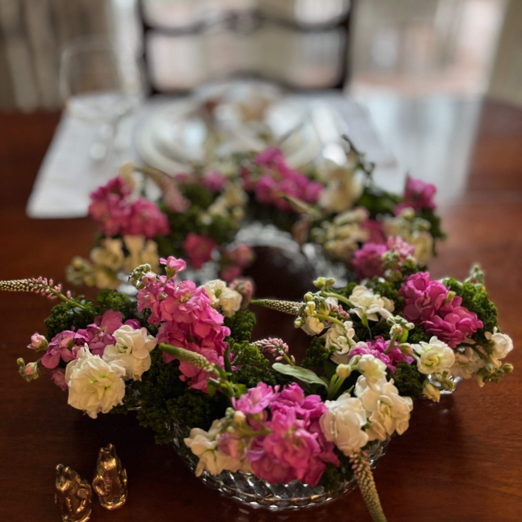 Hot pink and white flowers in a low oval vintage vessel on a dining table