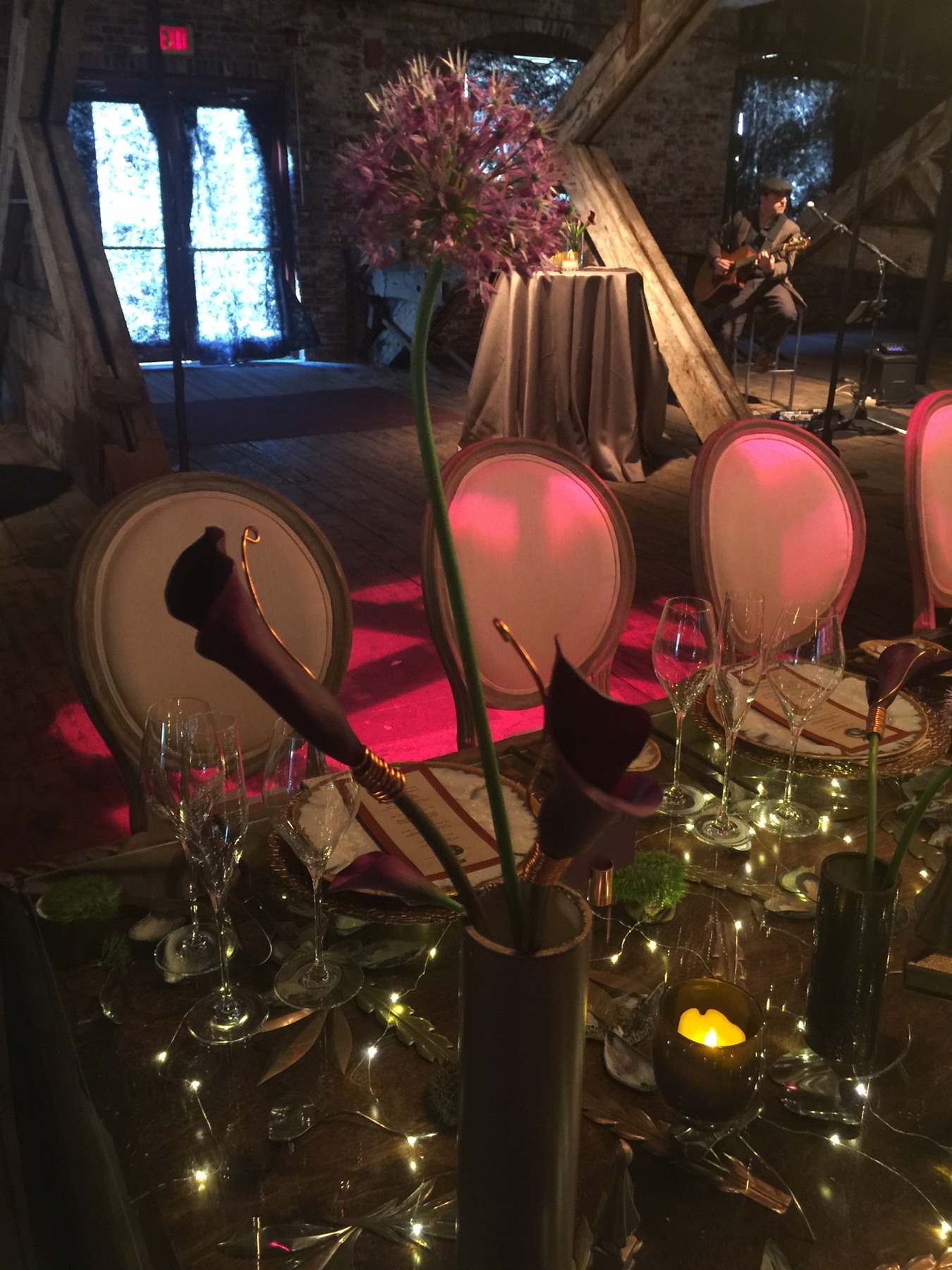 A candlelit table with red floral details and upholstered chairs