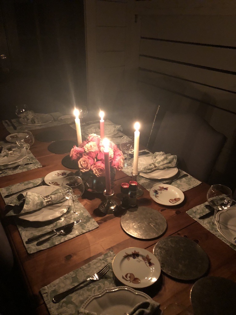 An intimate dinner table with pink flowers and lit taper candles