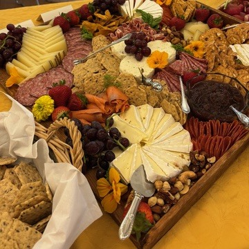 Cheeses, crackers, fruit and charcuterie arranged on a generous grazing board