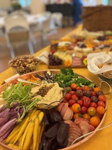 Colorful vegetables and dip with grazing platters in the background