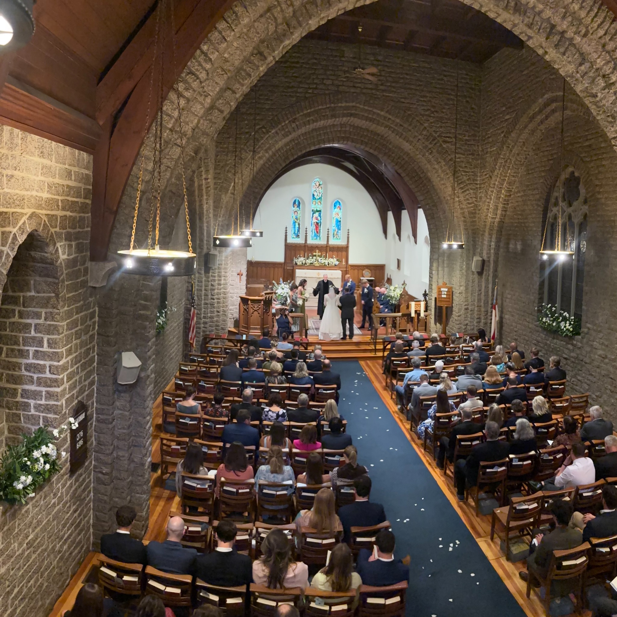 View from the balcony of the wedding ceremony, guests and floral arrangements throughout St. Mary’s stone church