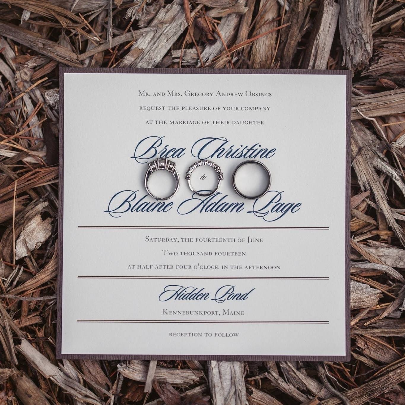 A cream wedding invitation with flowing script and wedding rings