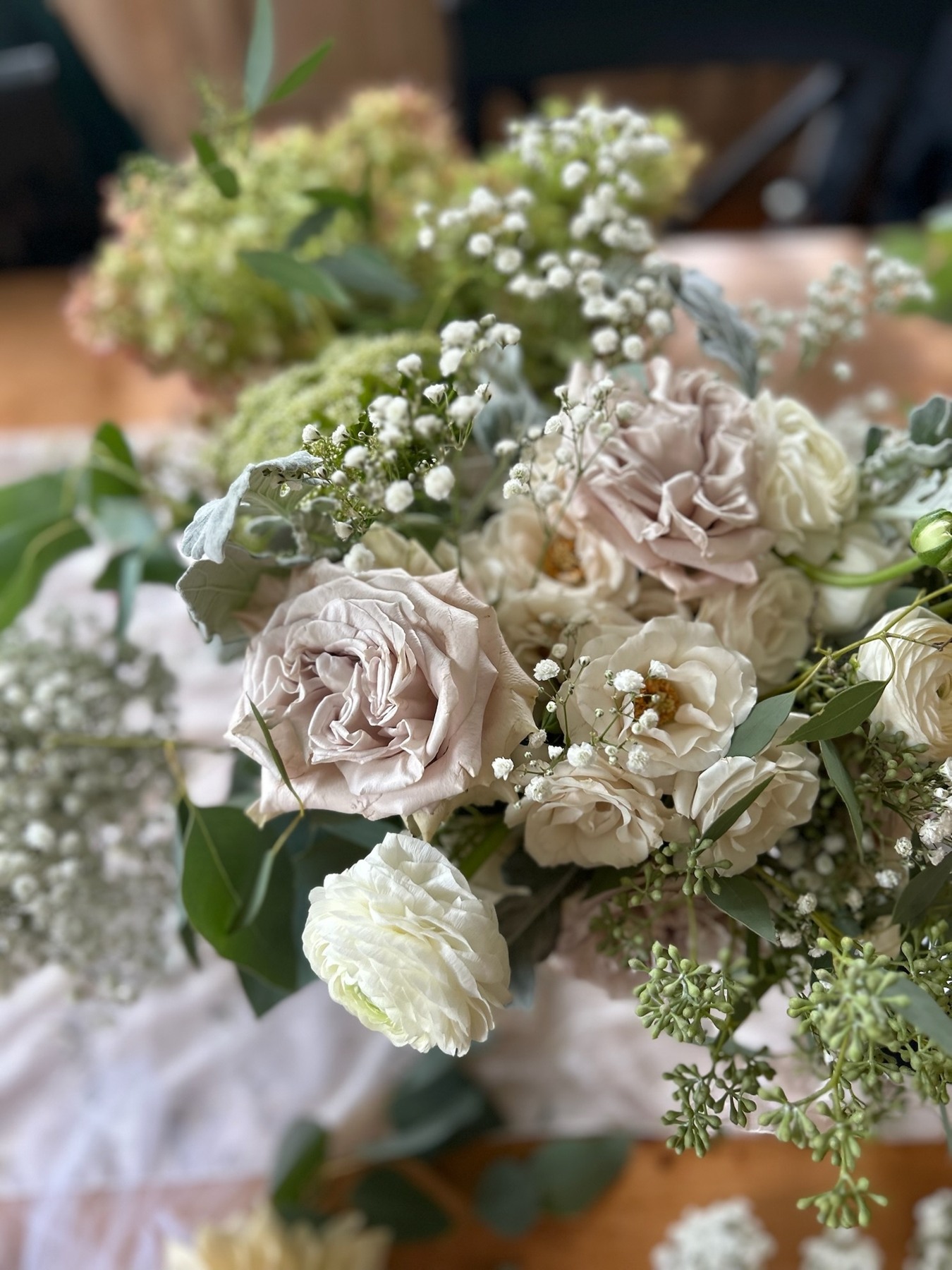Blush roses, white flowers and delicate greenery seen close up
