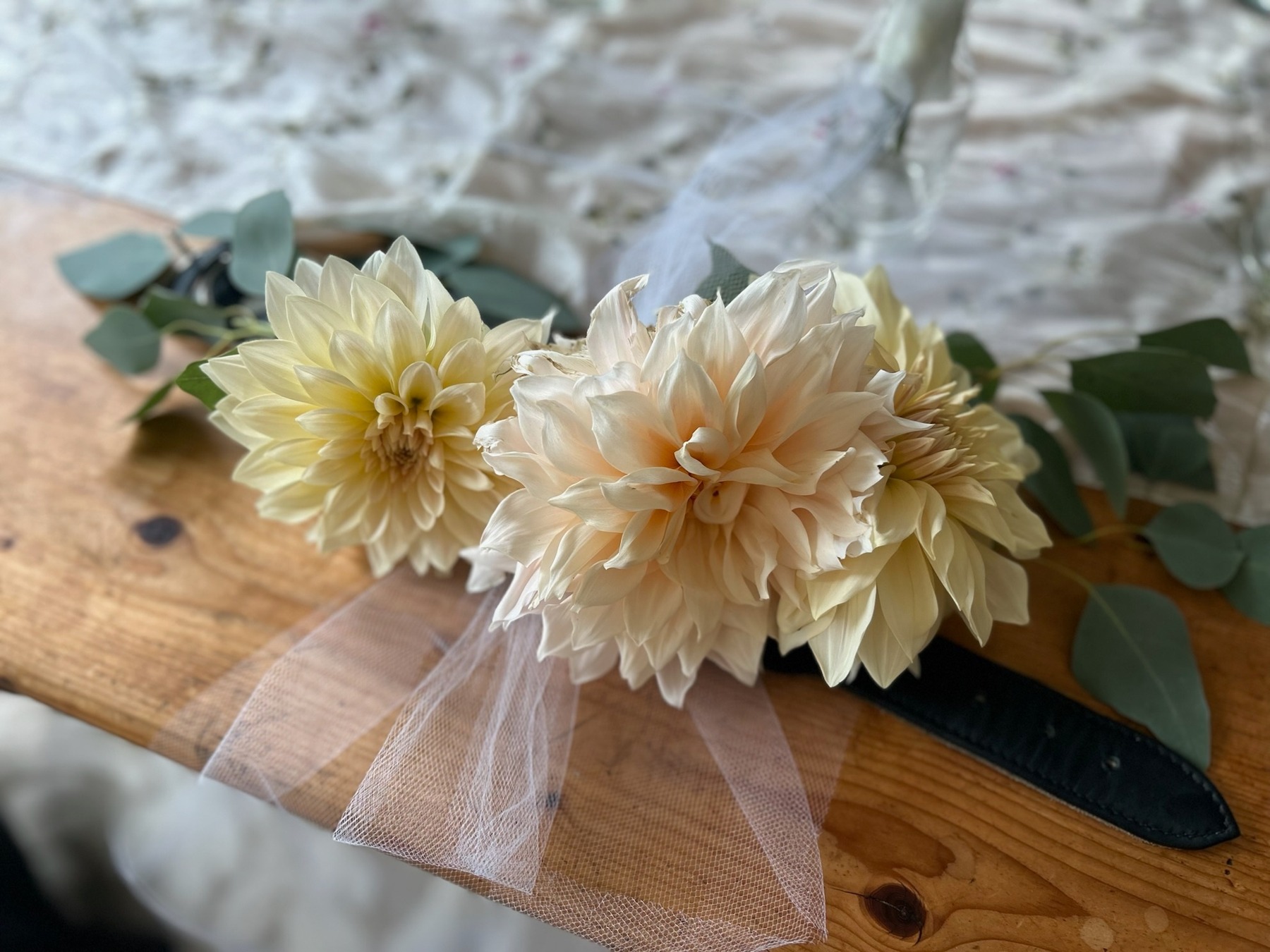 A dog collar decorated with pale dahlias, greenery and soft pink tulle for a wedding